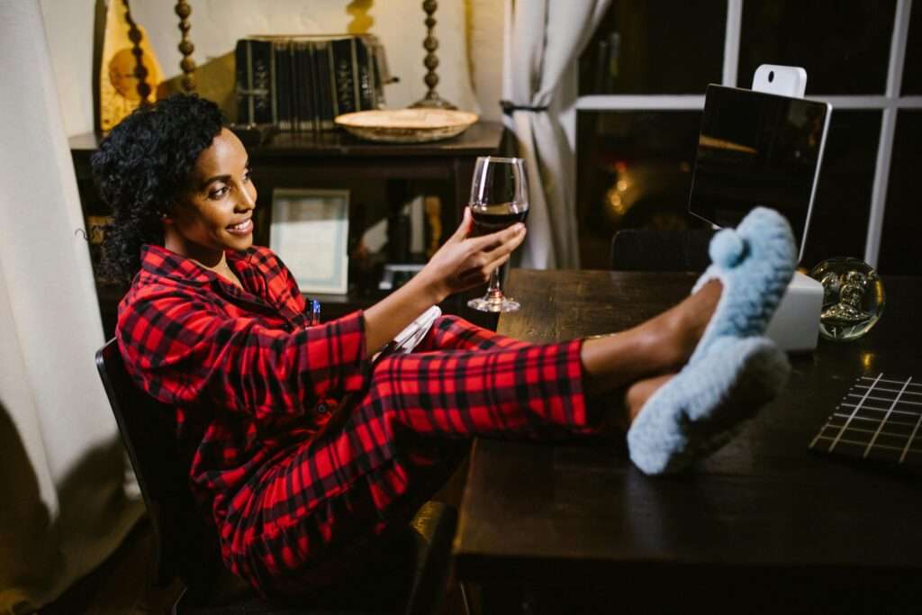 a red shirt girl working on laptop and wearing cross slippers 