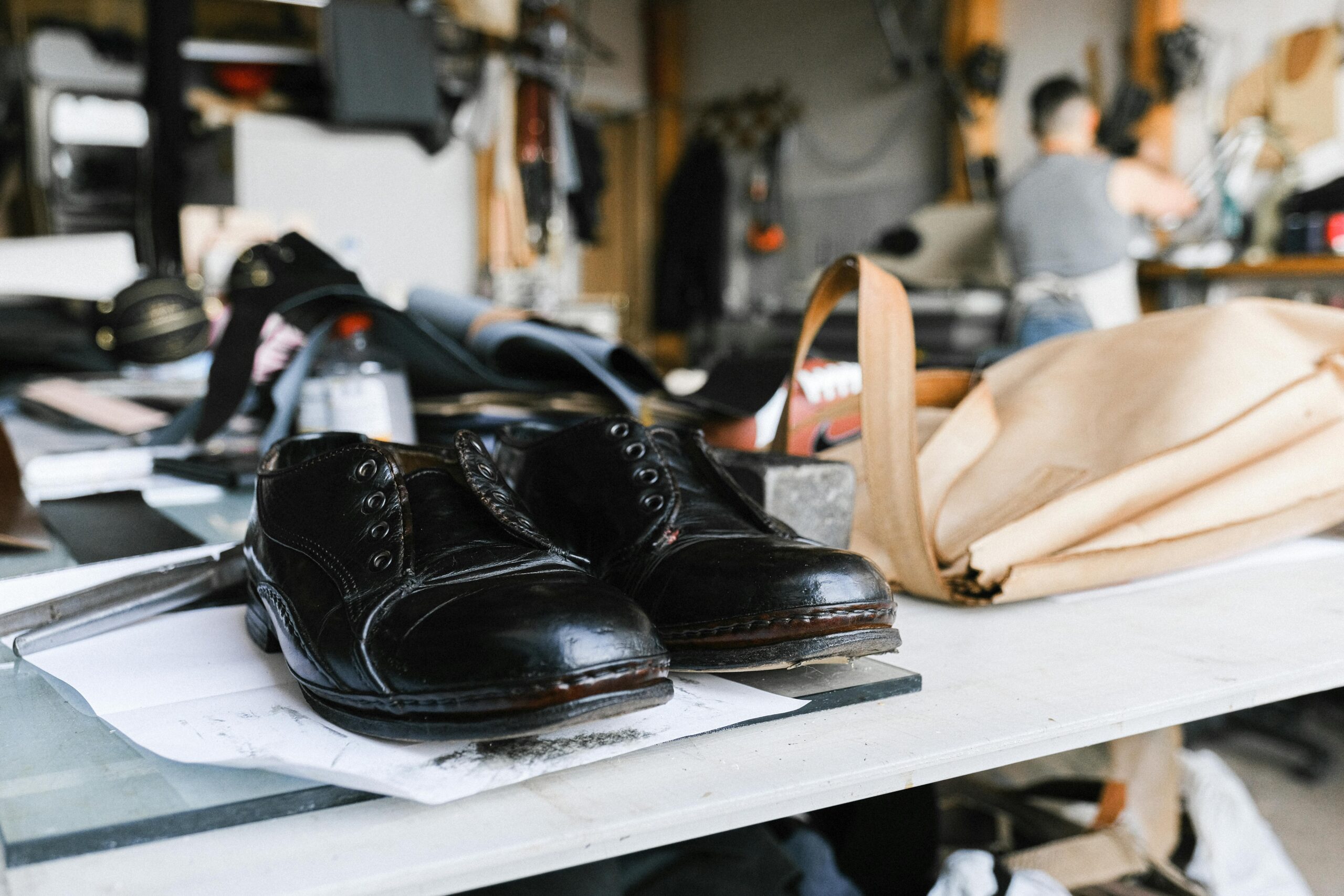 Image of a cobbler repairing a leather shoe on a workbench.